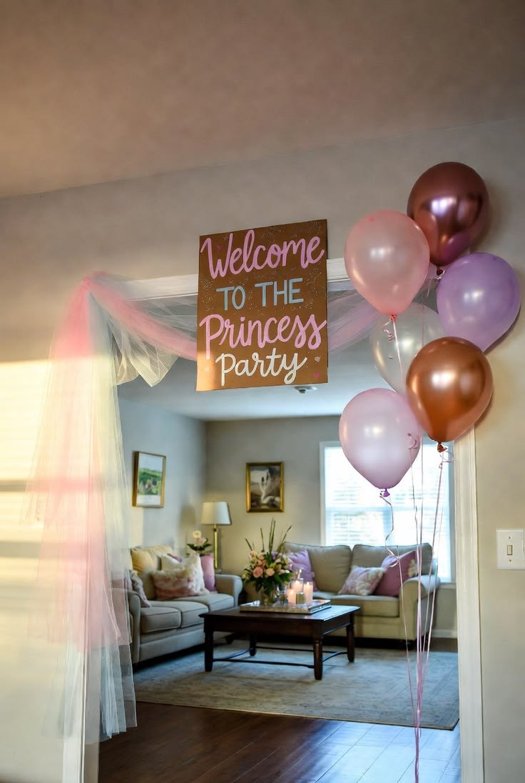 Doorway draped in pink tulle with a hand-lettered Welcome to the Princess Party sign and a bunch of pink, rose-gold and lilac balloons.