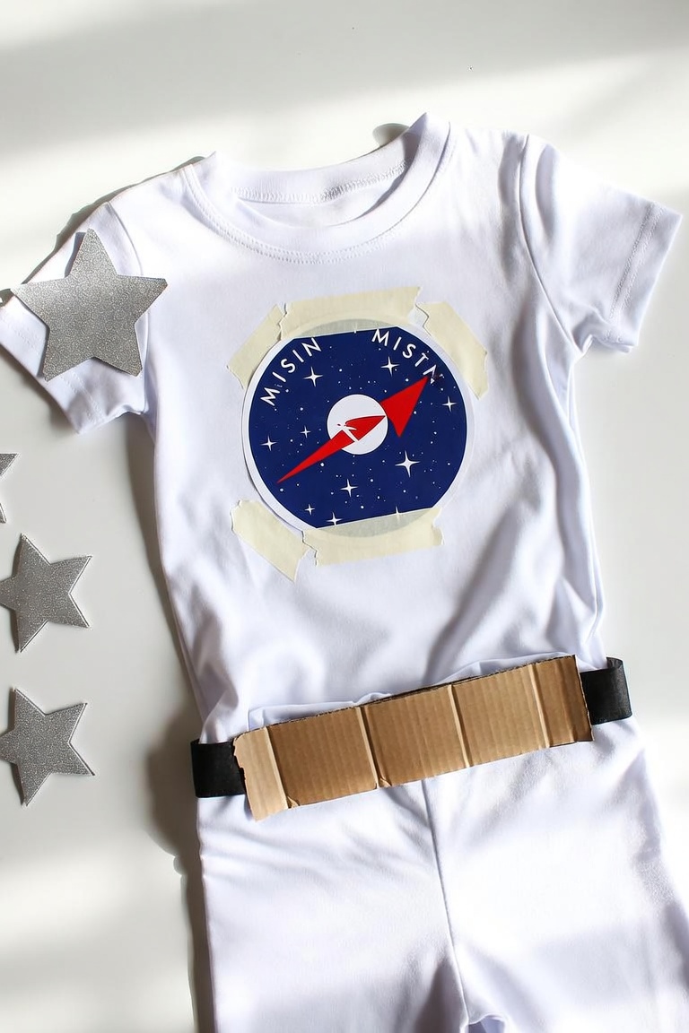 DIY astronaut costume with white outfit, printed mission patch and cardboard belt control panel