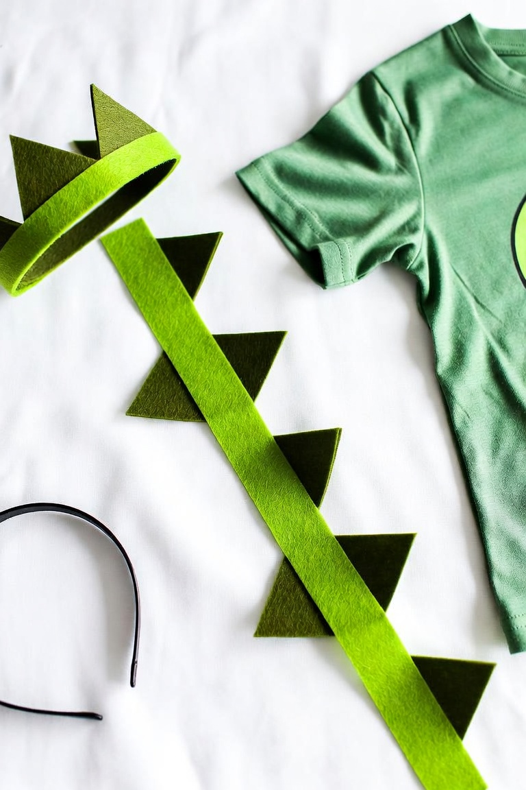 DIY dinosaur costume with green felt spike tail and spike headband on a green t-shirt