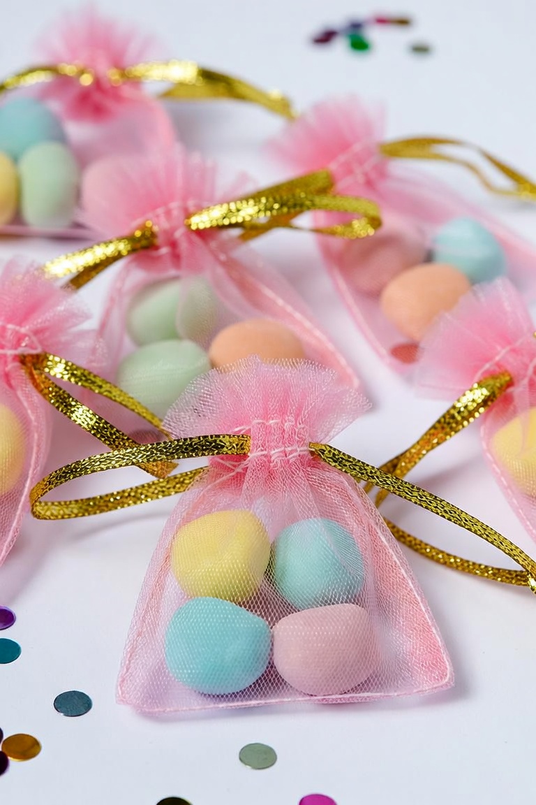 DIY party favor organza bags filled with pastel candy and tied with gold ribbon