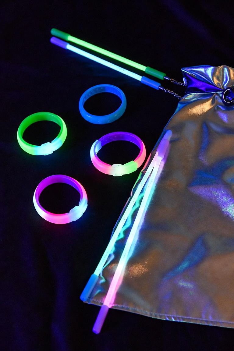 Glow sticks and glow bracelets in green, blue and pink with a silver favor bag on a dark background.